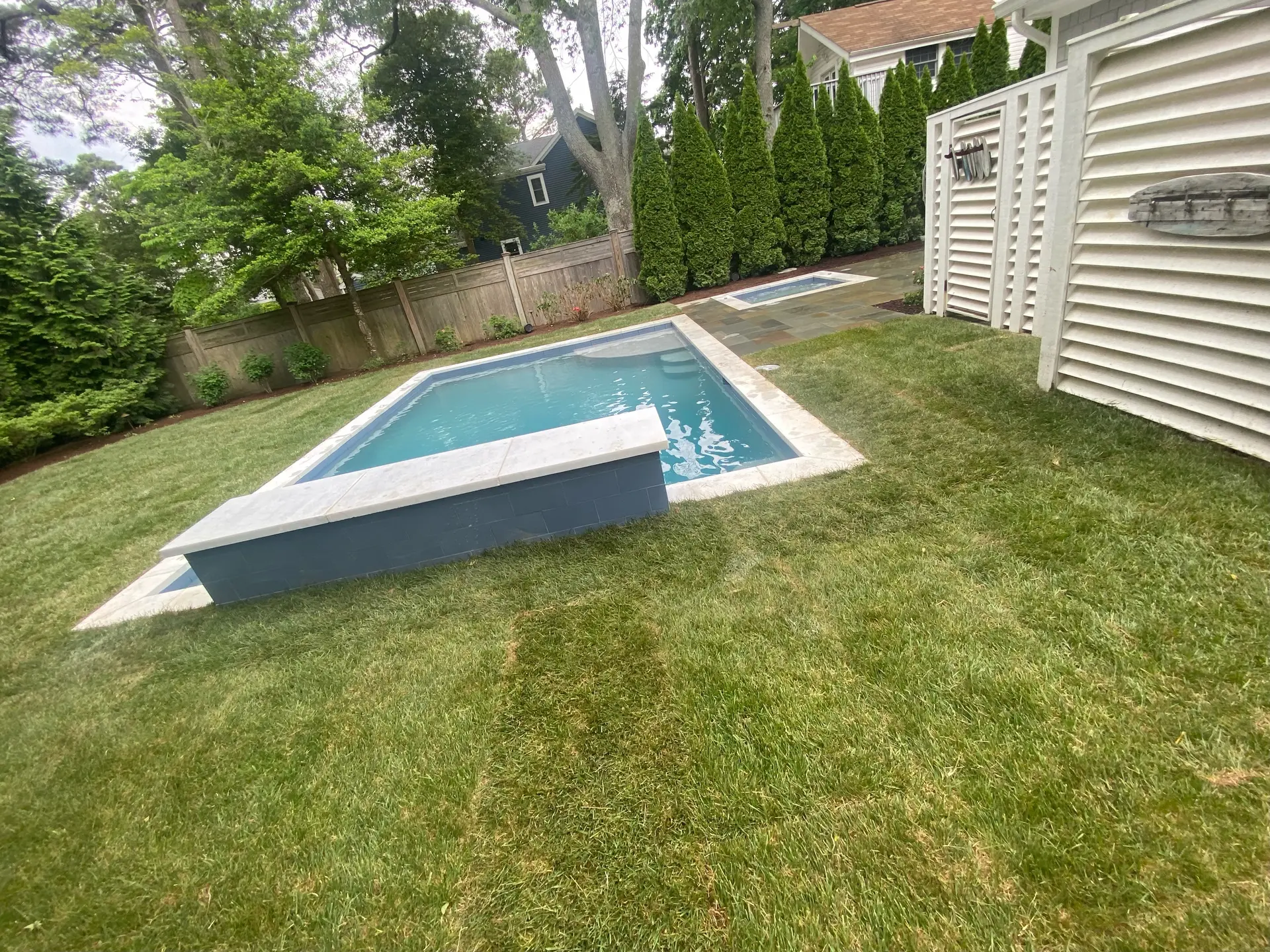 Modern backyard swimming pool hardscaping by DM Hardscapes