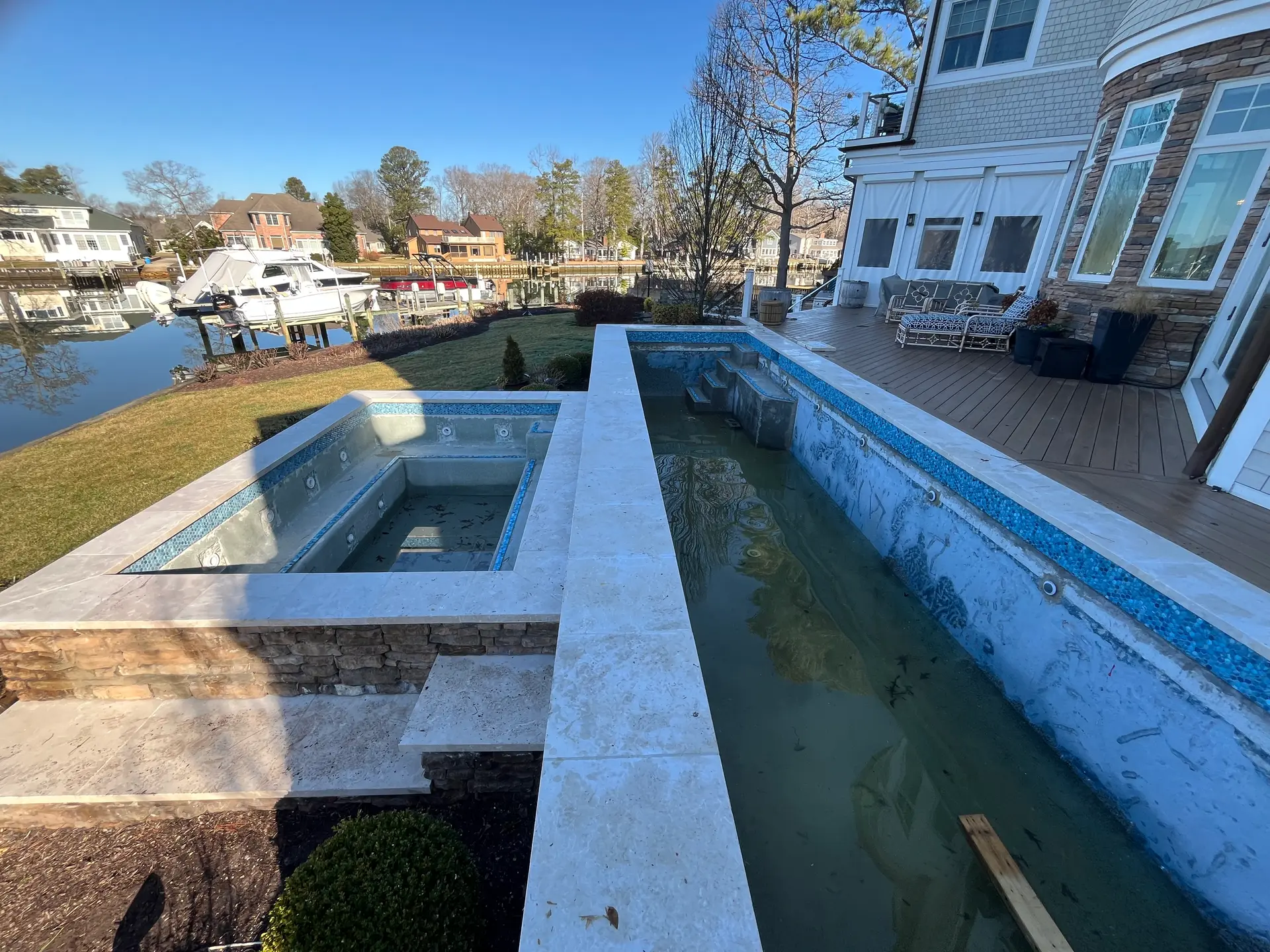 Waterfront luxury pool and spa with travertine deck overlooking the bay